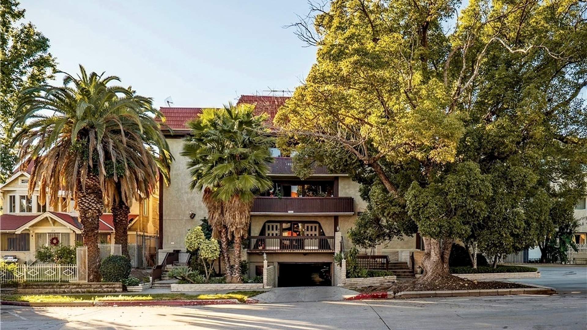 1825 N Gramercy Pl, a 1968 three-story Hollywood apartment building with tuck-under parking, photographed from the street.