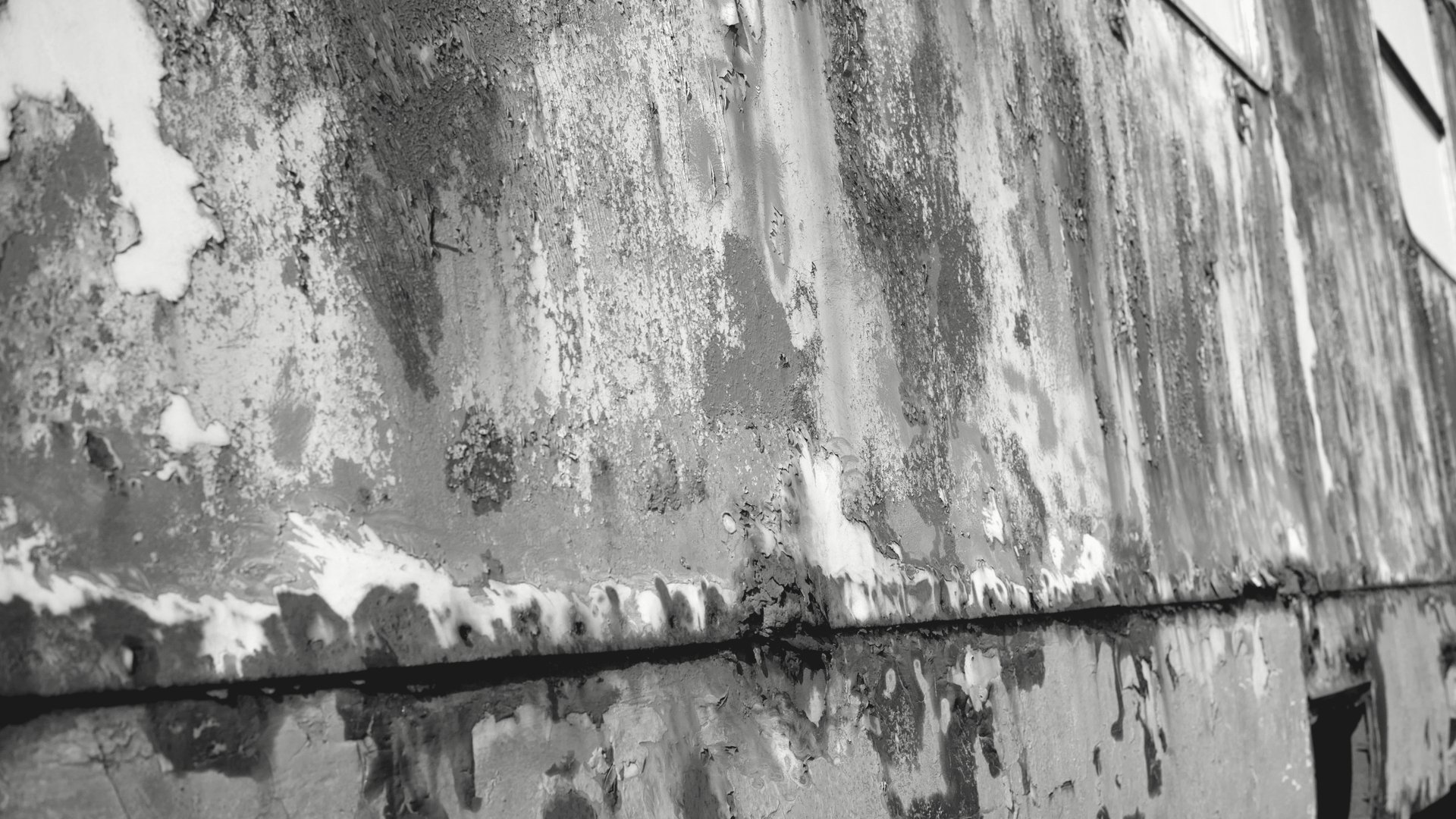Peeling exterior paint on wood siding of a 1940s West LA courtyard building, revealing bare wood substrate beneath the failed paint layer.