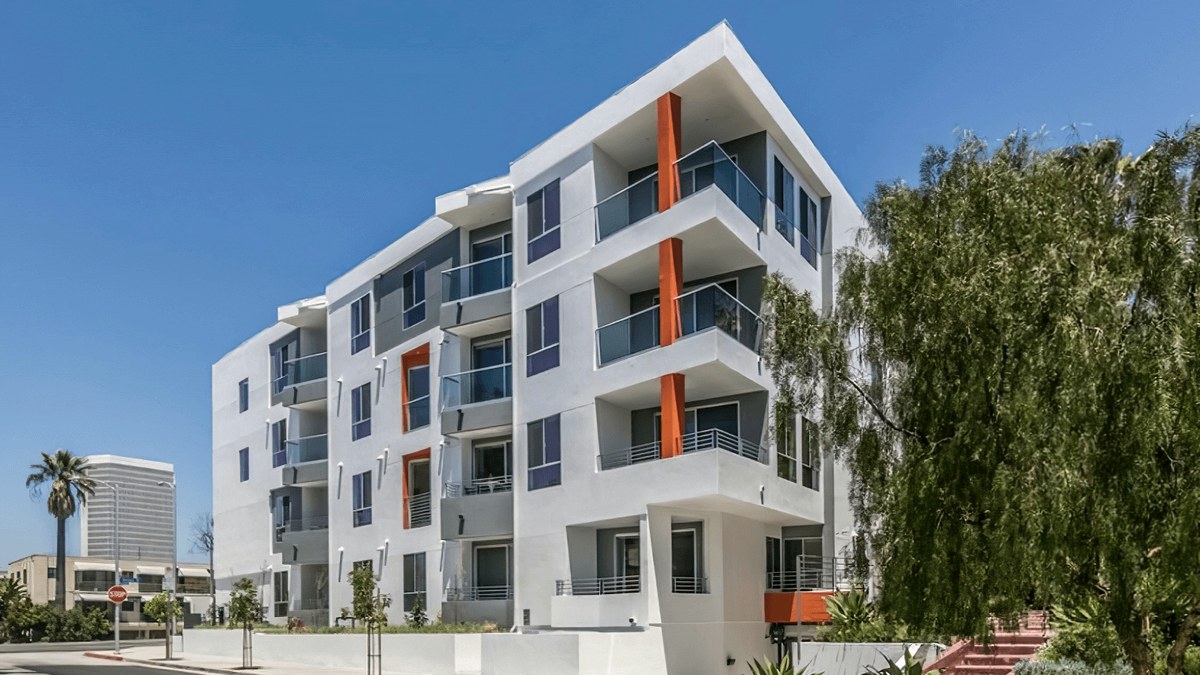 Olympic Towers — a four-story white multifamily building with orange accent bands and cantilevered balconies, Mid-City West.